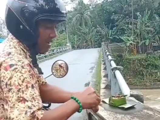 Viral! Momen Pria Santuy Santap Telur Sesajen di Jembatan